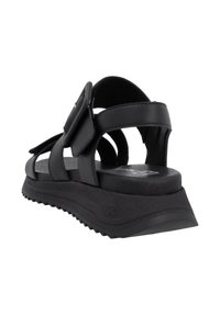 Sandalo in pelle nera con diverse cinghie, fibbia regolabile e suola in gomma testurizzata con un leggero rialzo.