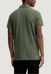 Ciemnozielona koszulka polo z klasycznym kołnierzykiem, krótkimi rękawami i rozcięciem z tyłu. Wykonana z miękkiego, oddychającego materiału.
