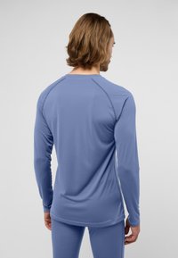 Langärmliges Sportshirt in Hellblau, aus einem weichen, glatten Stoff. Verfügt über Raglanärmel und Flatlock-Nähte für Komfort und Passform.
