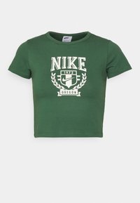 Crop top en coton vert à manches courtes, arborant un logo Nike blanc et le texte "1972" et "OREGON" dans un design d'emblème circulaire.