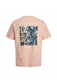 hele-roosa t-särk musta ja sinise botaanilise trükiga ristkülikuga seljal ning valge tekst "ORIGINALS" kujunduse kohal.