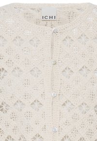 Cream-colored crochet cardigan with scalloped edges and white buttons down the front, branded ICHI on the label.