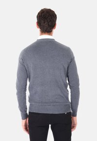 Maglione grigio in un materiale morbido e textured con una vestibilità slim, polsini e orlo a costine; la vista posteriore mostra un design semplice senza abbellimenti.
