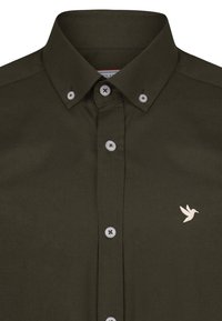 Camisa verde oliva de botones con un cuello corto, botones claros y un pequeño bordado de un pájaro blanco en el área del pecho izquierdo.