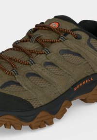 Chaussure de randonnée Merrell marron et noire avec des lacets orange et une semelle robuste conçue pour les terrains extérieurs.