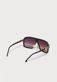 Gafas de sol negras con herrajes dorados, forma cuadrada, lentes púrpura degradados y patillas gruesas con una superficie texturizada y detalle de logo.