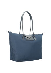 Sac fourre-tout bleu marine en tissu résistant, avec un accent en cuir triangulaire en haut, de longues poignées en cuir et un intérieur spacieux.