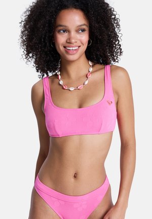 Haut de bikini rose vif avec encolure carrée et larges bretelles, présentant un motif floral texturé et un petit logo en forme de cœur.