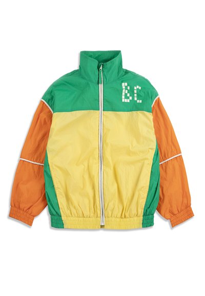 Veste coupe-vent en blocs de couleurs vert, jaune et orange avec col montant, poignets et ourlet élastiques, fermeture éclair à l'avant, et logo géométrique blanc "BC" sur la poitrine.