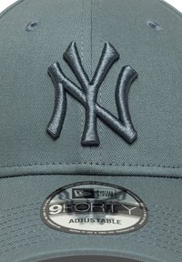Világosszürke baseball sapka, állítható, a frontján sötétszürke hímzett NY logóval, texturált anyagból készült, és kör alakú New Era matricával.