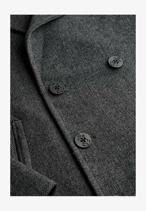 Blazer gris en espiga con botones negros que presentan un diseño de ancla, mostrando una tela texturada y ajustada con solapas clásicas.