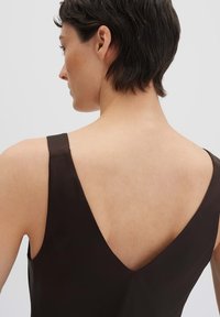 Abito senza maniche di un marrone scuro con uno scollo a V profondo, caratterizzato da una texture liscia e linee pulite, che mette in risalto un design minimalista.