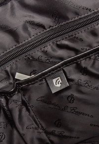 Zwart satijnen interieur met een subtiel logopatroon. Beschikt over een met rits afsluitbare pocket, een glanzende zilveren trekker en een gestikte stoflabel.