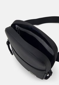 Borsa a tracolla nera realizzata in materiale sintetico texture, con chiusura a zip, tracolla regolabile e ampio interno senza tasche esterne.