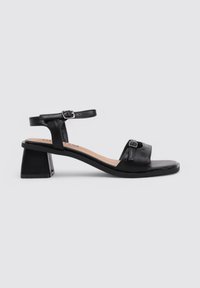 Sandalia de cuero negro con un diseño de puntera abierta, tacón cuadrado, correa de tobillo ajustable y acento de hebilla rectangular.