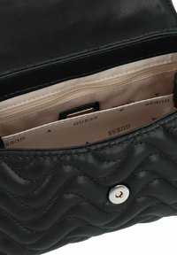 Borsa a tracolla nera trapuntata con esterno in pelle liscia, dotata di chiusura a scatto in argento, e un interno foderato in tessuto beige con tasche.