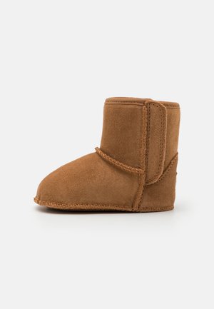 Tan suede boot with a rounded toe, short shaft, stacked seam detailing, and a soft texture. Features minimalistic design and no visible hardware.