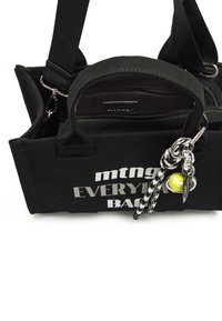 Zwarte canvas handtas met zilveren tekst "mtng EVERYBODY BACK." Heeft dubbele handvatten, ritssluiting en een zwart-wit geblokte sleutelhanger met een tennisbal charm.
