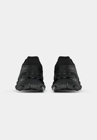 Μαύρα αθλητικά παπούτσια με επάνω μέρος από χωρίς ραφές υφάσματος, μαλ�ακή επένδυση στον αυχένα και υφασμένο καουτσούκ σόλα με ορατά σχέδια πρόσφυσης.