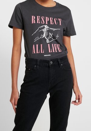 Person iført en sort t-shirt med pink tekst "RESPECT ALL LIFE" og hvid håndillustration, kombineret med sort højttaljede jeans.