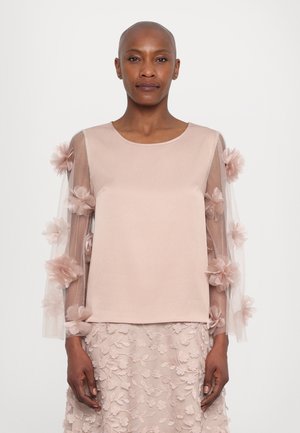 Pale pink blouse featuring sheer sleeves adorned with fabric flowers and a smooth body. Accompanied by a matching embroidered skirt.
