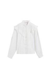 Blusa blanca con cuello volado, botón al frente y mangas largas. La tela texturizada presenta sutiles líneas verticales.