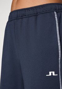 Jūras spēku sporta šorti ar elastīgu jostu, kontrastējošām baltām šuvēm un mazu logotipu kreisajā apakšējā stūrī. Gluda tekstūra.