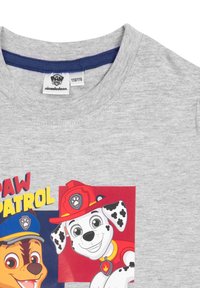 T-shirt in cotone grigio con grafiche colorate di "Paw Patrol" che raffigurano due cani cartoon, uno con un cappello blu e l'altro con un casco da pompiere rosso.