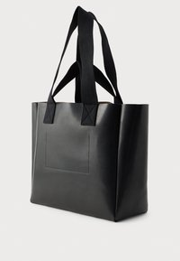 Saco tote preto feito de couro liso com duas alças em tecido, formato retangular, apresentando um detalhe de bolso frontal cosido.