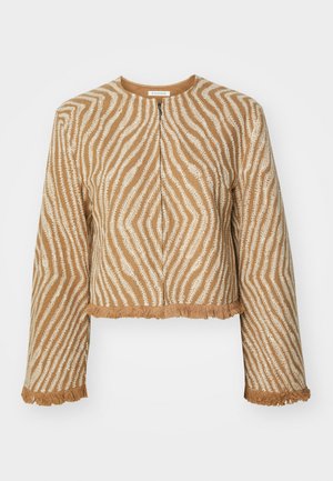 Kort, cropped jakke lavet af struktureret beige stof med hvide zigzag mønstre og frynsede kanter på ærmer og kant. Lynlås foran.