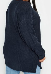 Langärmliger navy Pullover mit strukturiertem Strickdesign, ausgestattet mit einem runden Ausschnitt, seitlichen Schlitzen und einer lässigen Passform.