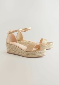Sandales compensées en cuir beige avec des brides et une semelle en jute tressé. Équipées d'une bride de cheville avec une boucle en métal. Design à bout ouvert.