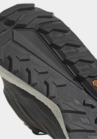 Gros plan d’une semelle de chaussure noire avec une bande de roulement rugueuse et texturée pour une meilleure adhérence et un bord de semelle intermédiaire blanc.
