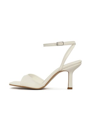 Sandale blanche à talon haut ouvert à l'avant avec fine bride de cheville et boucle, talon moyen, et semelle intérieure rembourrée sur fond blanc uni.