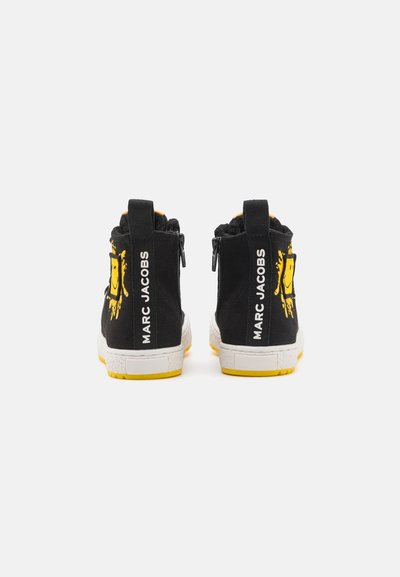 Sneakers alte in tessuto nero con accenti gialli, caratterizzati da un design con faccina sorridente e suole texturizzate bianche. Zip posteriori e dettaglio con logo.