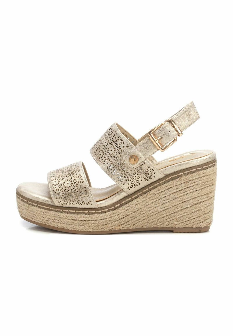 Sandalia cuña con correas sintéticas doradas perforadas, hebilla ajustable y suela envolvente de yute. Plantilla suave de color claro.