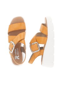 Sandales en cuir jaune avec de larges brides entrecroisées, boucle en argent et semelle épaisse blanche. Texture lisse et design arrondi.