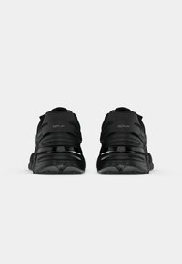 Black sporty shoes feature a sleek design with a textured upper, chunky sole, and reflective accents. Logo positioned on the heel.