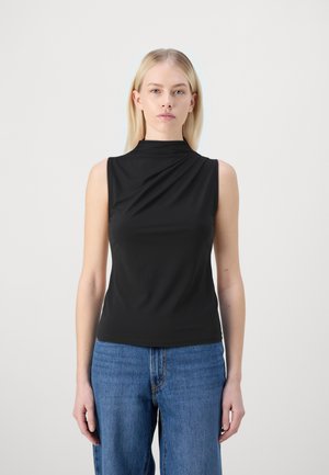 Schwarzes ärmelloses Top mit hohem Kragen, das ein drapiertes Vorderdesign aufweist. Hergestellt aus glattem, dehnbarem Stoff. Kombiniert mit blauer Jeans.