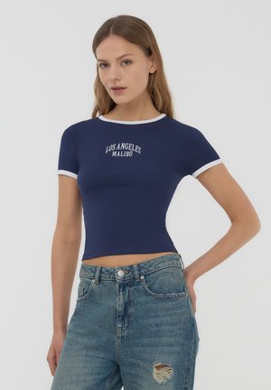 T-shirt cropped blu navy realizzato in tessuto elasticizzato, con colletto e bordo maniche bianchi, con la scritta "LOS ANGELES MALIBU" stampata in bianco.