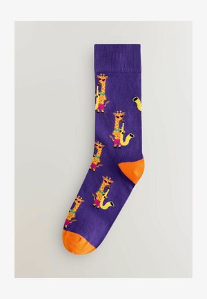 Chaussettes violettes avec un motif de girafe ludique, rehaussées de touches vives de jaune et de rose. Les zones des orteils et des talons sont orange.