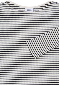 Gestreepte lange mouwen top in crème en marineblauw, met een geribbelde textuur en een borstzakje. Etiket zegt "CECIL."