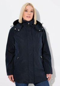Marinblå vattentät jacka med dragkedja framtill, justerbar huva och sidofickor med dragkedja. Har en mjuk yta och figurnära design.