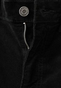 Czarne spodnie z metalowym guzikiem i zamkiem błyskawicznym. Charakteryzują się miękką fakturą oraz precyzyjnym przeszyciem wzdłuż szwów. Zamek błyskawiczny w srebrnym odcieniu.