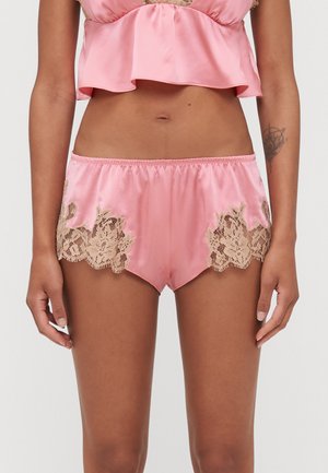 Pink satin shorts with scalloped edges, featuring intricate beige lace accents on the sides and an elasticated waistband for comfort.