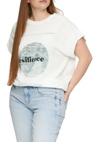 Weißes Baumwoll-T-Shirt mit kurzen, aufgeschlagenen Ärmeln, das ein kreisförmiges Wassermuster und schwarzen Text mit der Aufschrift "Resilienz" auf der Vorderseite zeigt.