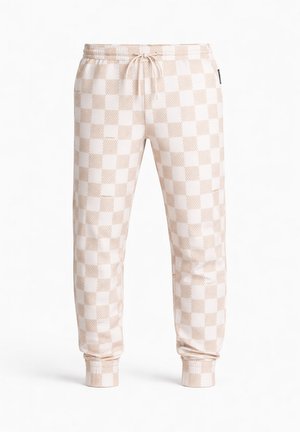 Beige-weiße karierten Jogginghosen mit elastischem Bund, Kordelzug, seitlichen Taschen und Bündchen an den Knöcheln vor weißem Hintergrund.