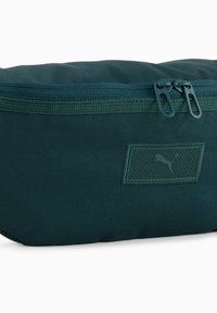 Borsetta in poliestere verde scuro con una superficie texturizzata, dotata di chiusura a zip e di una patch con il logo Puma al centro.