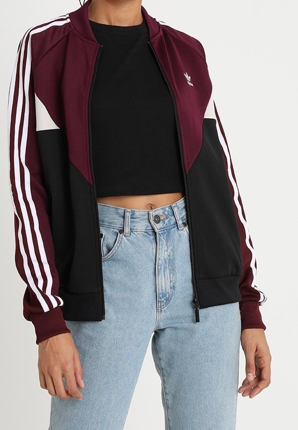 Jacka med dragkedja i vinröd och svart färgkombination, med vita ränder på ärmarna. Tillverkad av mjukt tyg med avslappnad passform.