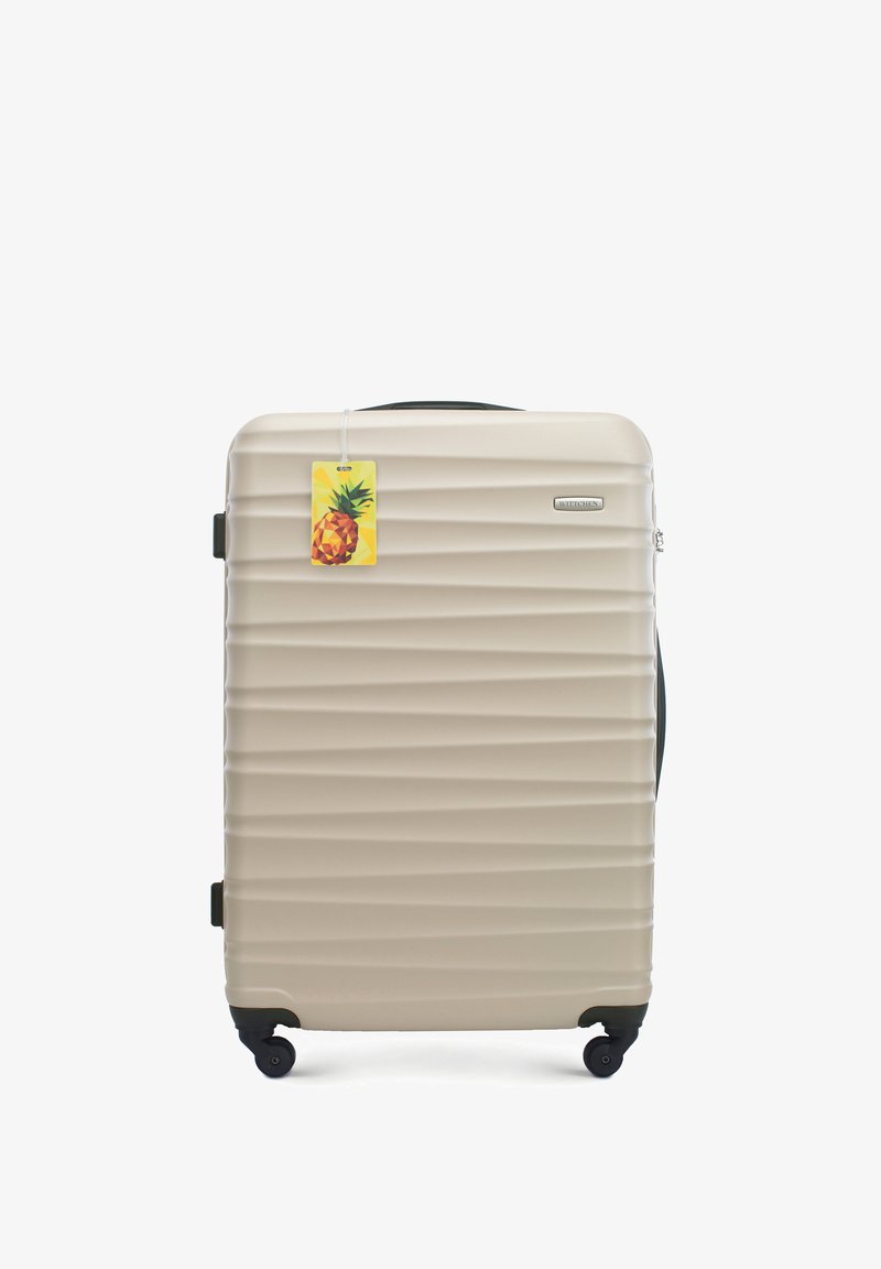 Valigia rigida beige con texture a righe, ruote nere, manico retrattile e un'etichetta gialla con un grafico di un’ananas.